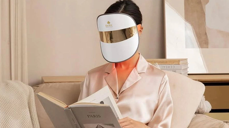Woman wearing a Dr Ivy Skincare London Regenerative skincare Energy LED Face mask - reading a book