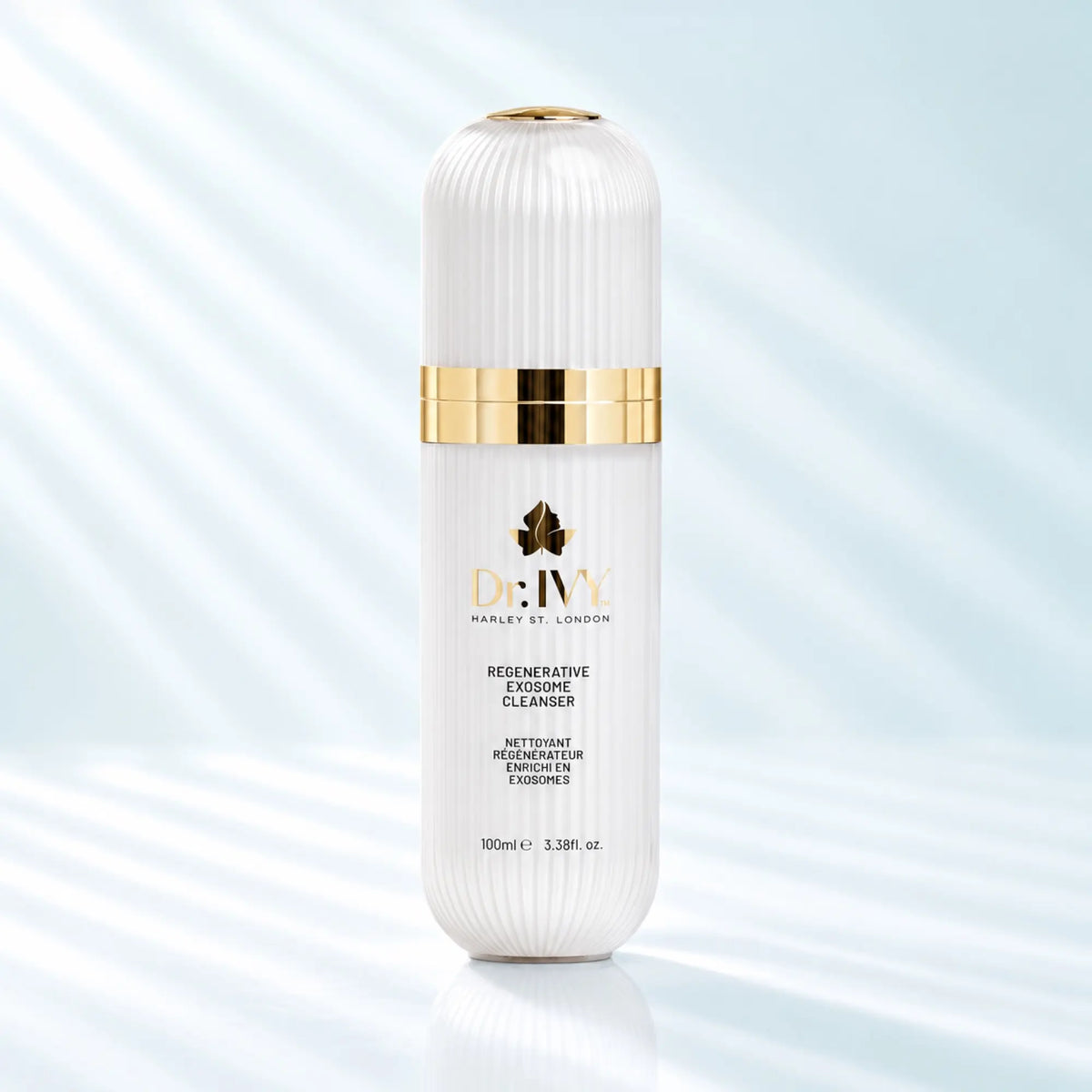 Dr Ivy Regenerative Exosome Cleanser 100ml in a white ribbed bottle with gold detailing against a pale aqua background.
