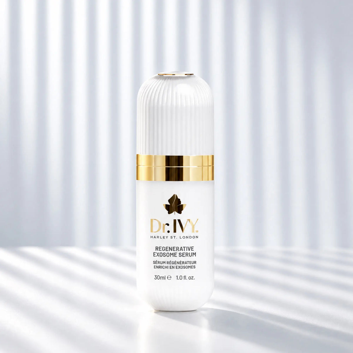 Dr Ivy Regenerative Exosome Serum 30ml in a white ribbed bottle with gold detailing against a softly striped white background.
